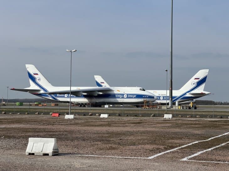 Two Volga-Dnepr Antonov An-124 freighters parked on a gravel apron at Leipzig/Halle Airport in March 2024