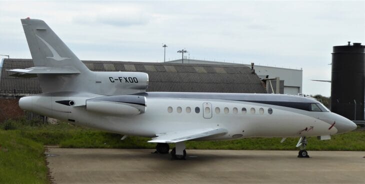 Dassault Falcon 900 C-FXOO parked on a ramp in front of a hangar