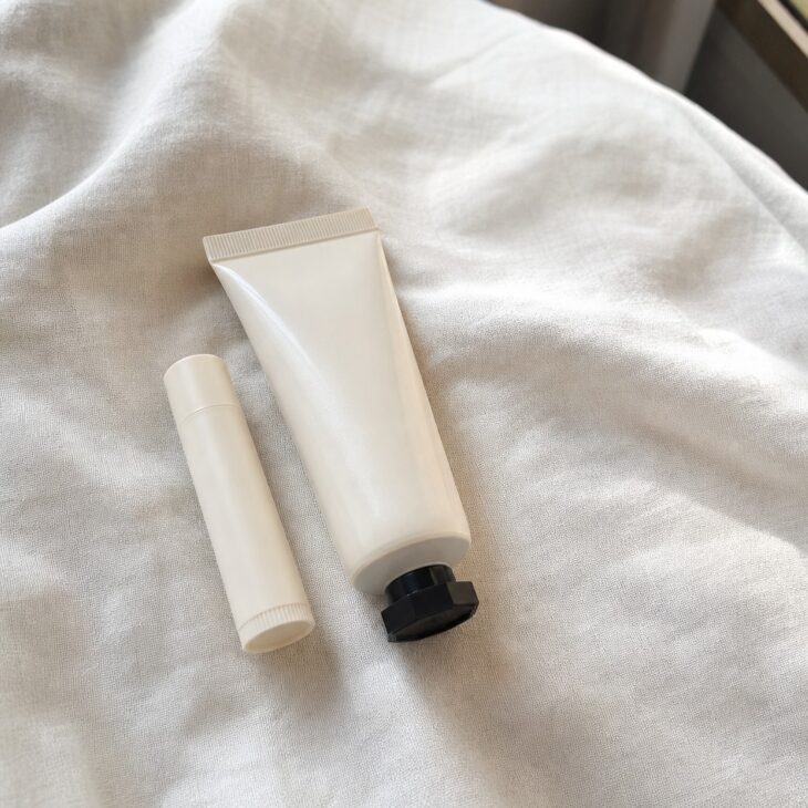 Lip balm tube and hand cream tube on pale linen