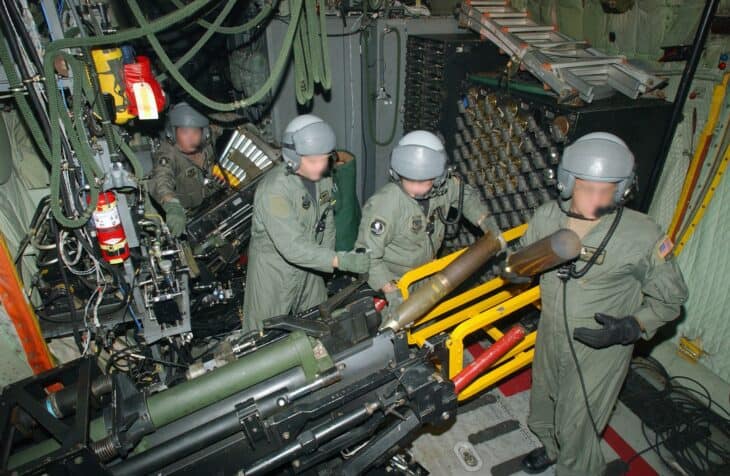 Aerial gunners working at the guns inside an AC-130U Spooky