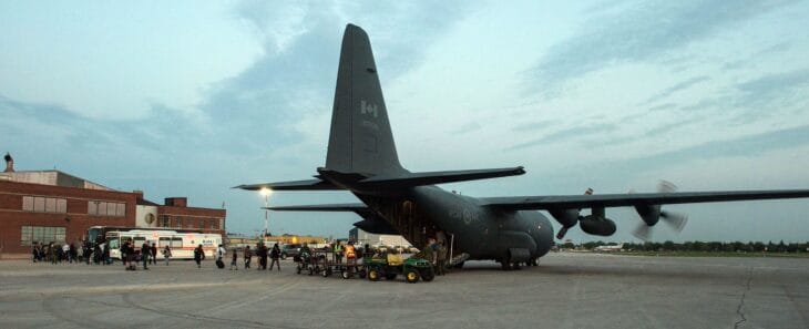 CC-130H Hercules 130338 on the ramp at Winnipeg with evacuees and ground vehicles beside it