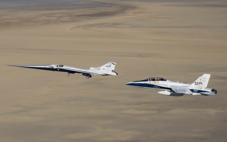 The X-59 flying beside an F/A-18 chase aircraft over the desert