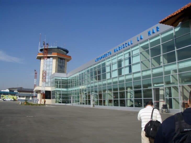 Glass-fronted terminal and control tower of Aeropuerto Mariscal La Mar in Cuenca, Ecuador, under a blue sky