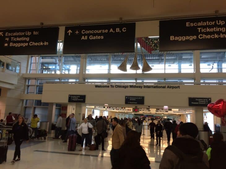 Passengers in the Chicago Midway terminal with signs for ticketing and baggage check-in
