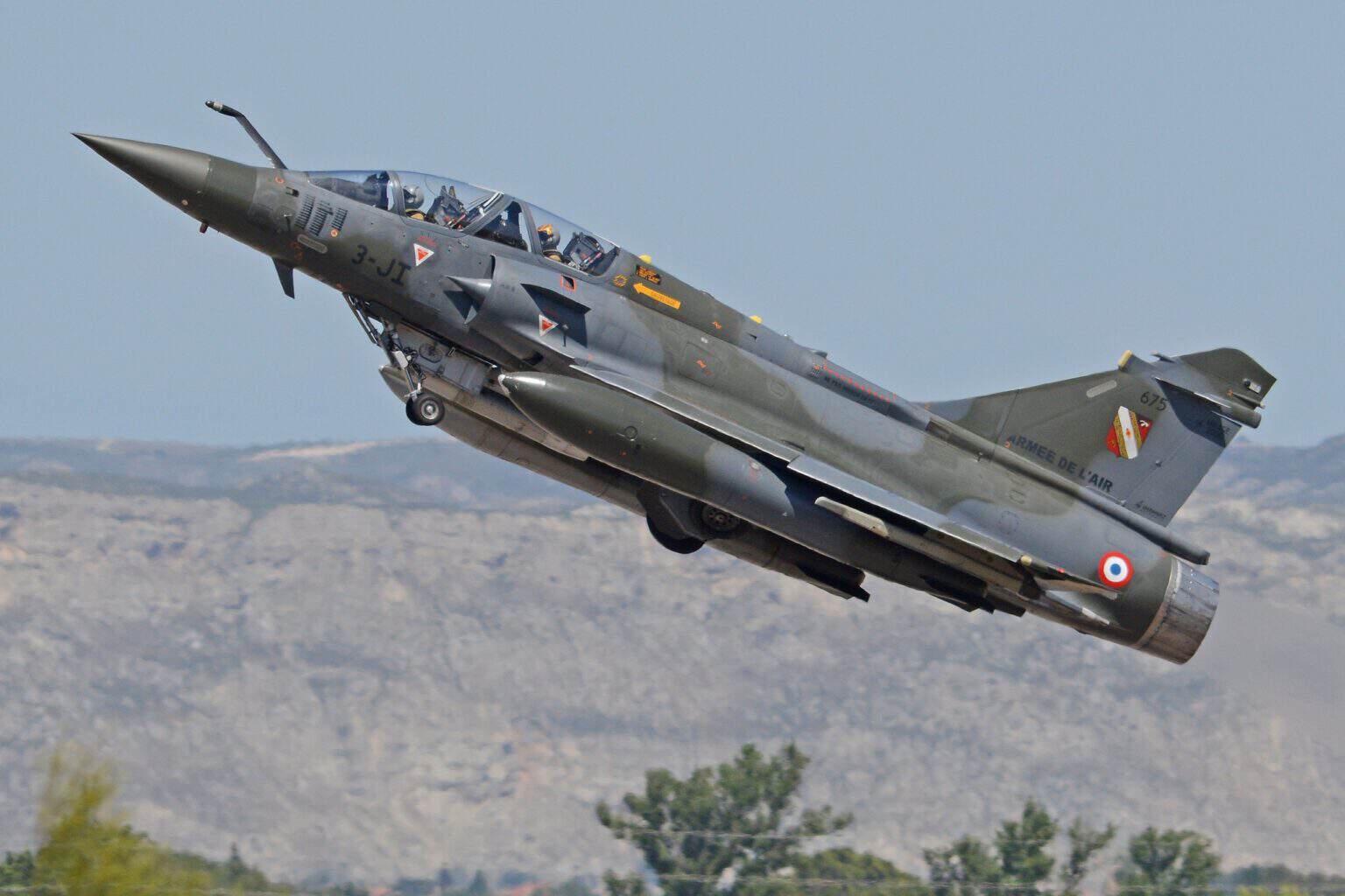 French Air and Space Force Mirage 2000D banking away after takeoff over hills