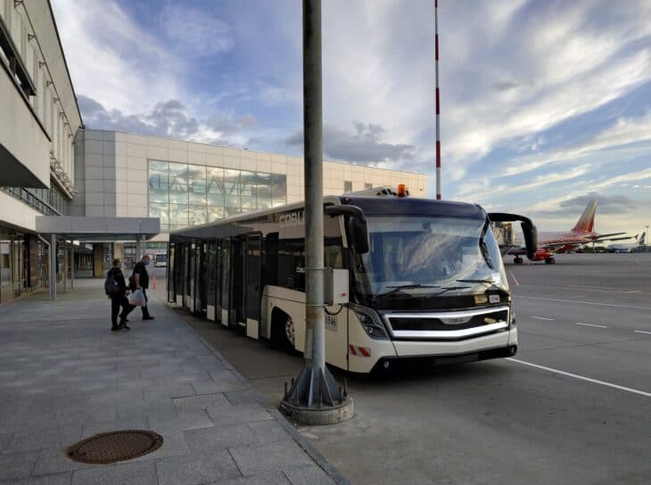 Apron bus and terminal building at St. Petersburg Pulkovo Airport with an aircraft in the background