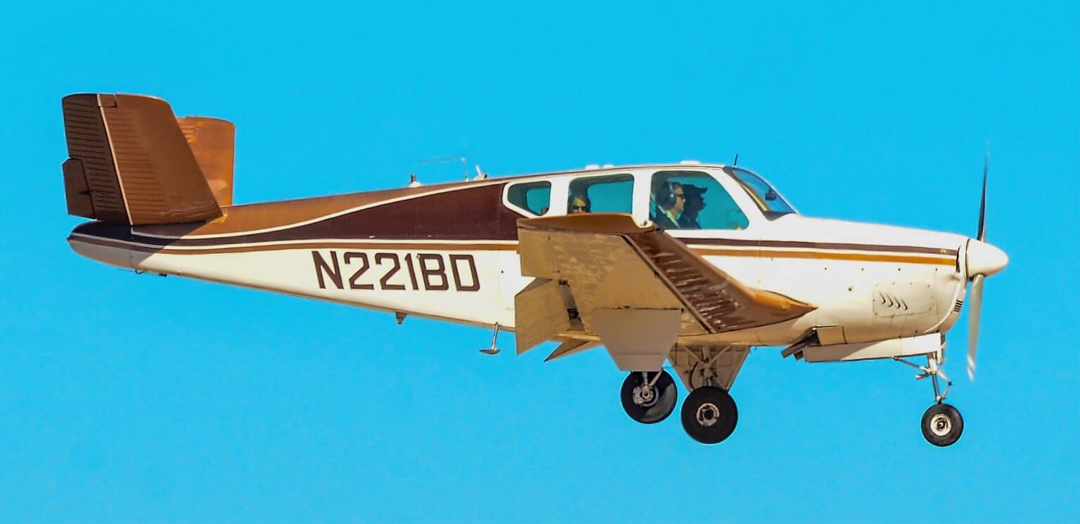 Beechcraft K35 Bonanza N221BD in flight with its landing gear extended near North Las Vegas Airport