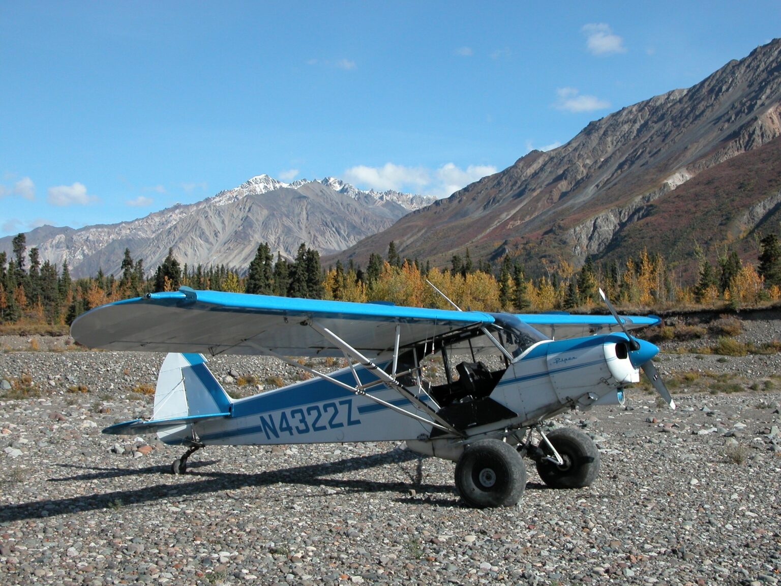 Piper PA-18 Super Cub on a gravel bar in Wrangell-St. Elias National Park, Alaska, with mountains behind