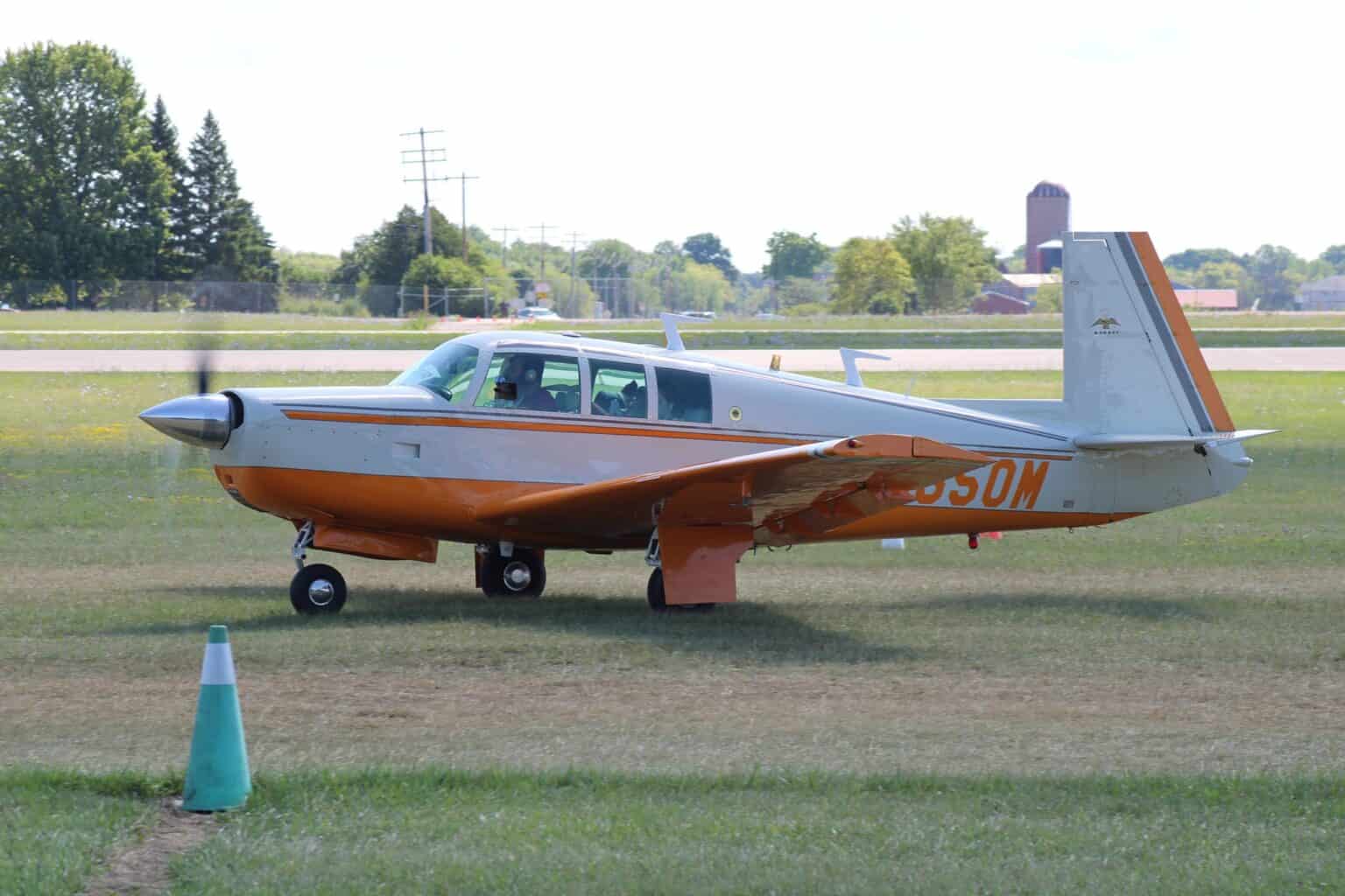Orange and white Mooney M20F Executive 21 N9550M parked on grass