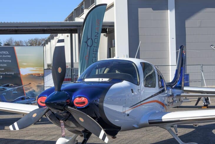 Blue and white Cirrus SR22 parked at an airshow with its propeller in front