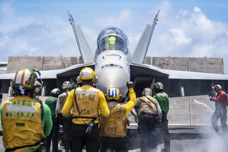 Flight deck crew guide an F/A-18F Super Hornet toward the catapult aboard USS Nimitz
