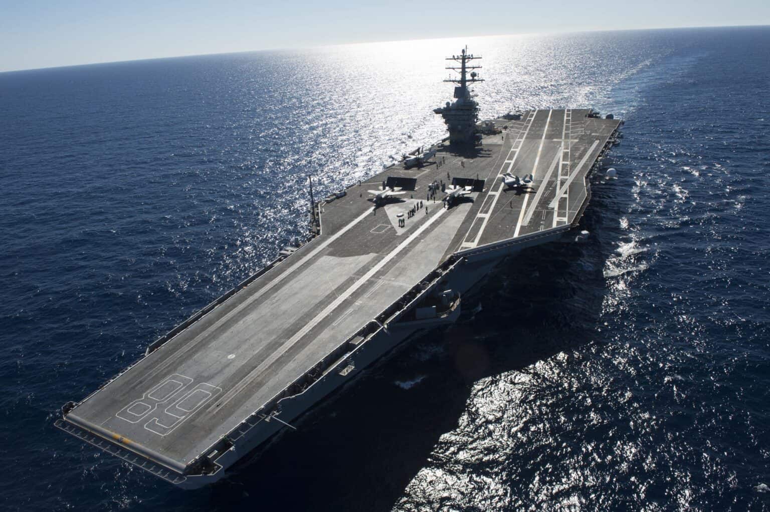 USS Nimitz (CVN-68) steaming under a glittering sun, seen from above with the hull number 68 painted on the flight deck