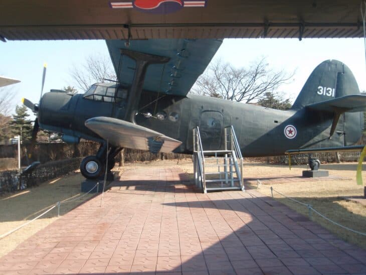 Antonov An-2 Colt biplane with North Korean red-star roundel and serial 3131 on display under a shelter