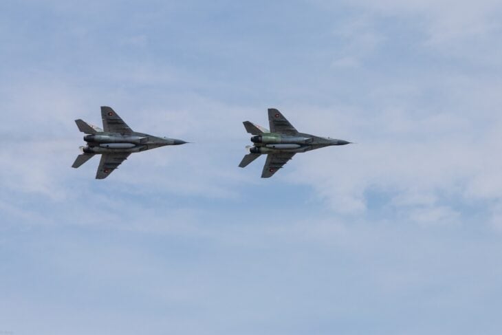 Two Mikoyan MiG-29 Fulcrum fighters flying side by side against a pale sky
