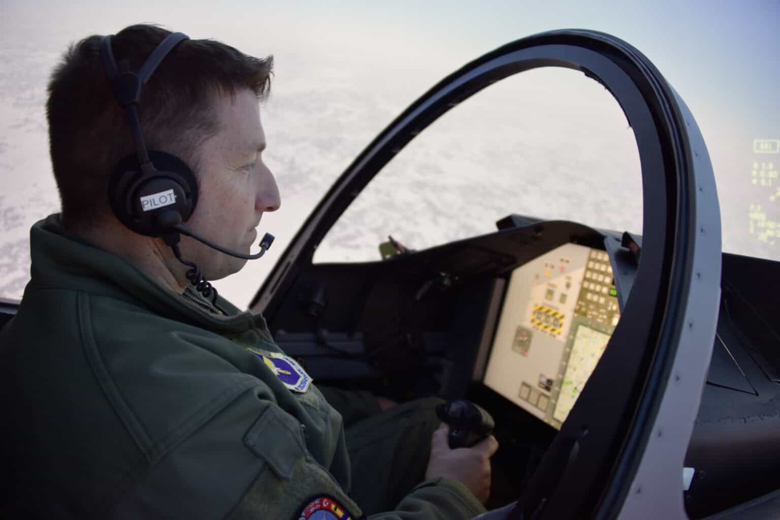 U.S. Air Force pilot in a flight suit and headset in a training simulator cockpit