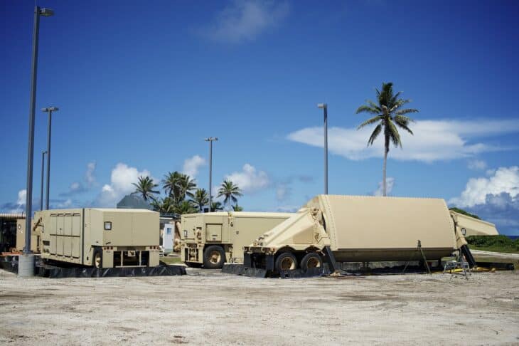 Tan AN/TPY-2 radar antenna on its trailer beside support trailers and palm trees on Kwajalein Atoll