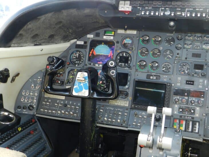 Flight deck of a Learjet 35 with two control yokes, analog flight instruments and the throttle quadrant between the pilot seats