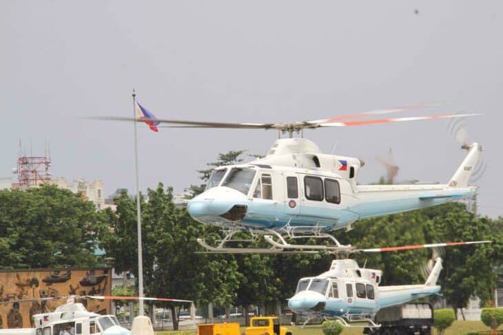 Philippine Air Force Bell 412EP helicopter in white and light blue hovering low beside a second Bell 412