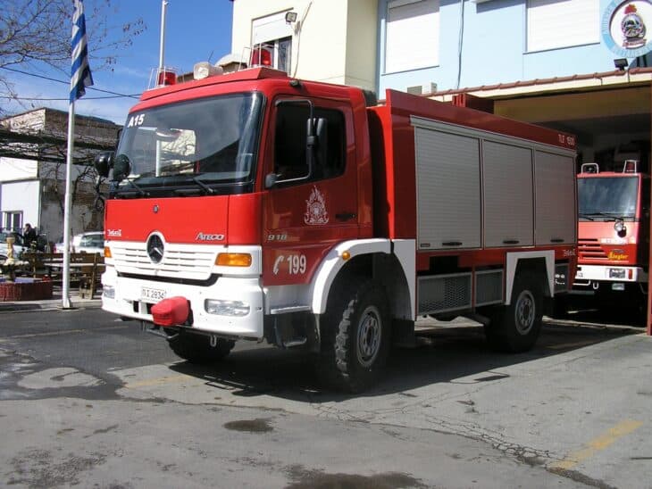 Red Hellenic Fire Service fire pump truck parked outside a fire station in Thessaloniki
