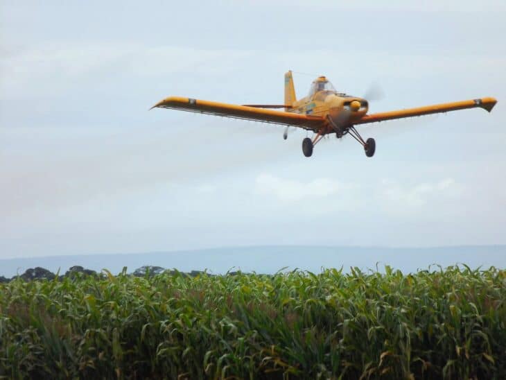 Agricultural aircraft banking low over a green crop field in Brazil