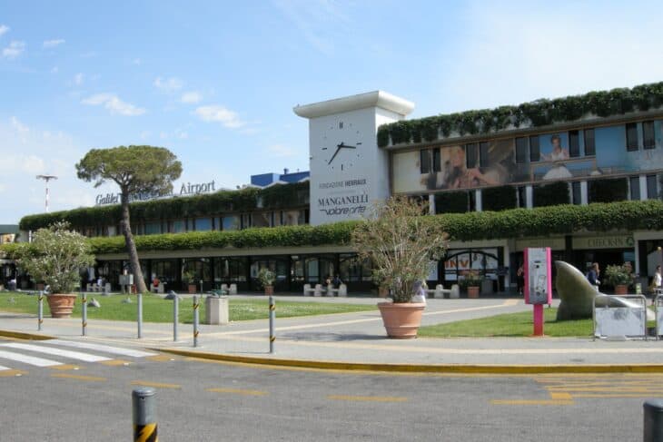 Front of the Galileo Galilei terminal at Pisa International Airport with its clock tower and green facade