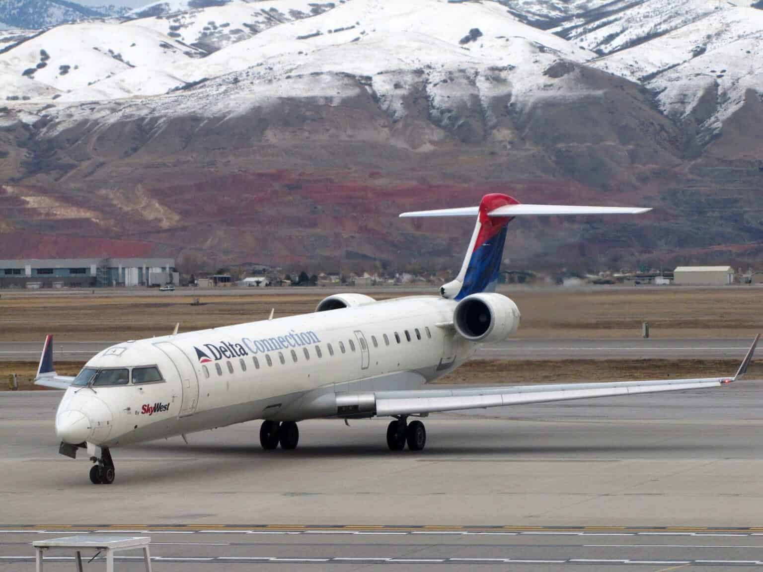 SkyWest Bombardier CRJ-700 taxiing at Salt Lake City International Airport with snow-covered mountains behind