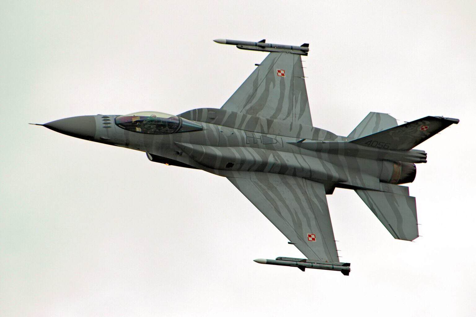 Polish Air Force F-16C in tiger-stripe display livery banking with missiles under its wings