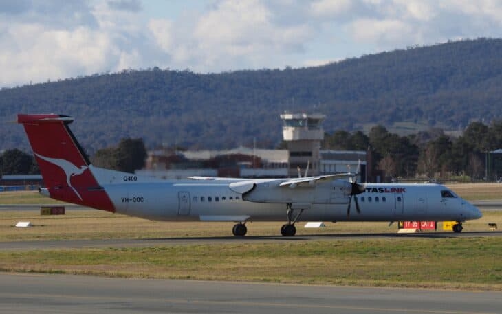 QantasLink Bombardier Dash 8-400 VH-QOC taxiing at Canberra Airport with the control tower and hills behind