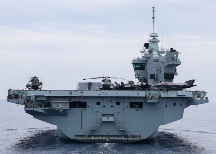 HMS Prince of Wales bow-on at sea with F-35B jets on deck and the twin islands on the starboard side