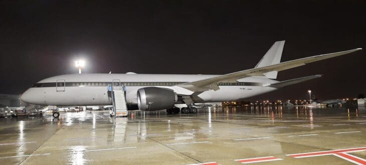 Boeing 787-8 P4-BDL on a rain-soaked ramp at night, registration visible under the tail