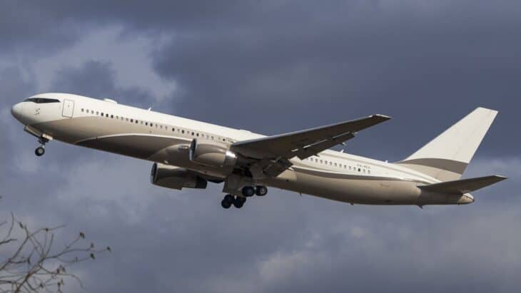 Boeing 767-300ER P4-MES climbing out after takeoff in a pale grey livery