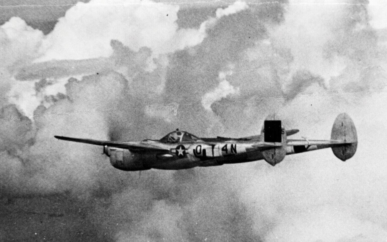 Lockheed P-38 Lightning banking through broken cloud in a wartime photograph