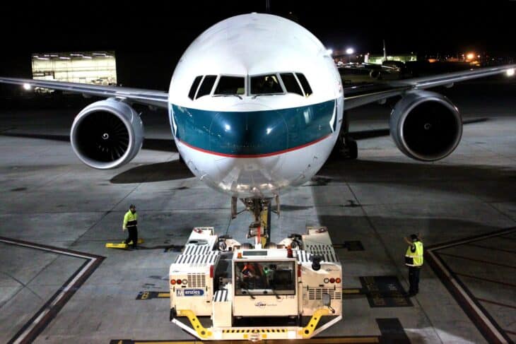 Head-on view of a Cathay Pacific Boeing 777-300ER on the ramp at night with a tug attached