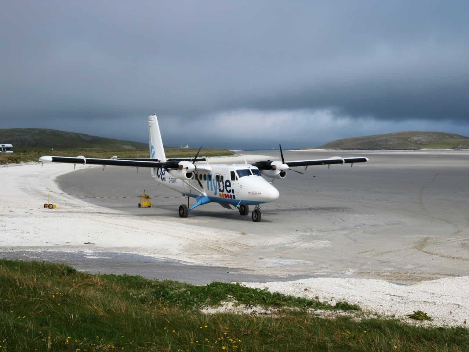 Loganair Twin Otter taxiing on the white sand of Barra's beach runway under dark storm clouds