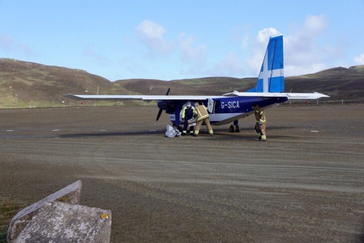Directflight Britten-Norman Islander G-SICA on the gravel strip at Fair Isle as crew work around it