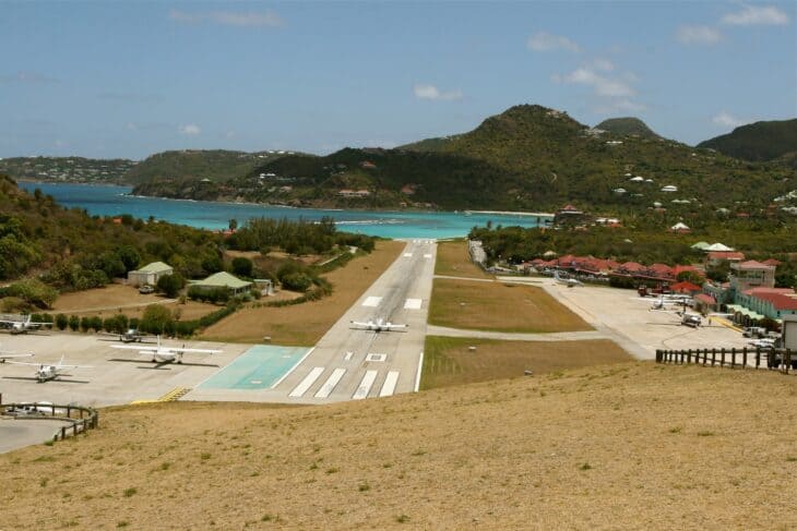 View along the runway at Gustaf III Airport, St. Barthélemy, with the hill at the approach end and the sea beyond