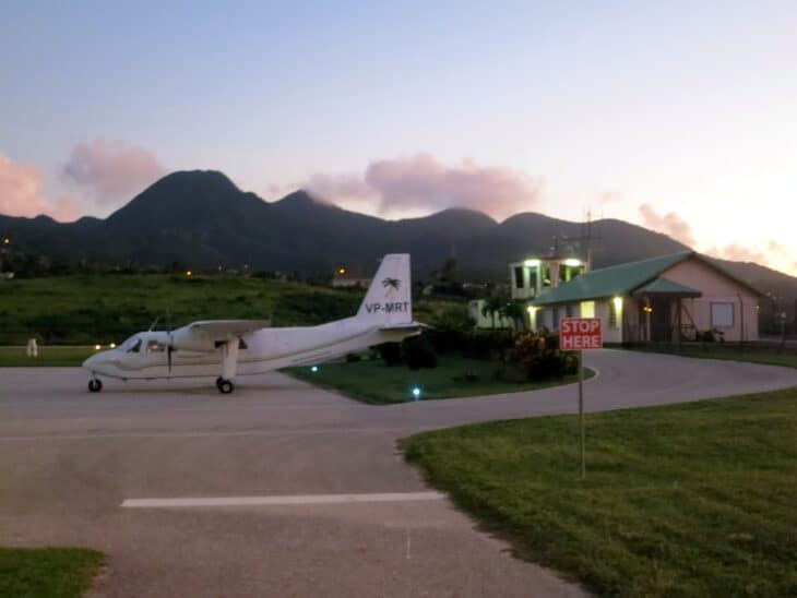 A Britten-Norman Islander parked outside the terminal at Montserrat's airport with the volcano behind
