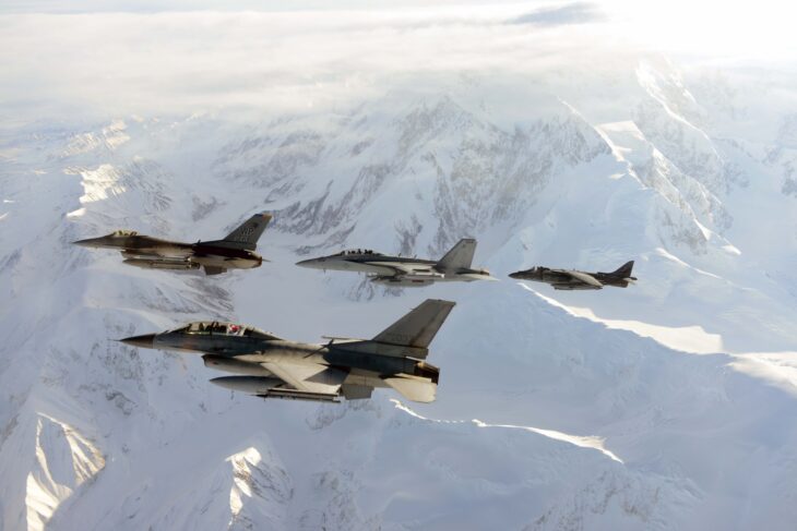 Four Republic of Korea Air Force KF-16 fighters flying in formation over snow-covered mountains