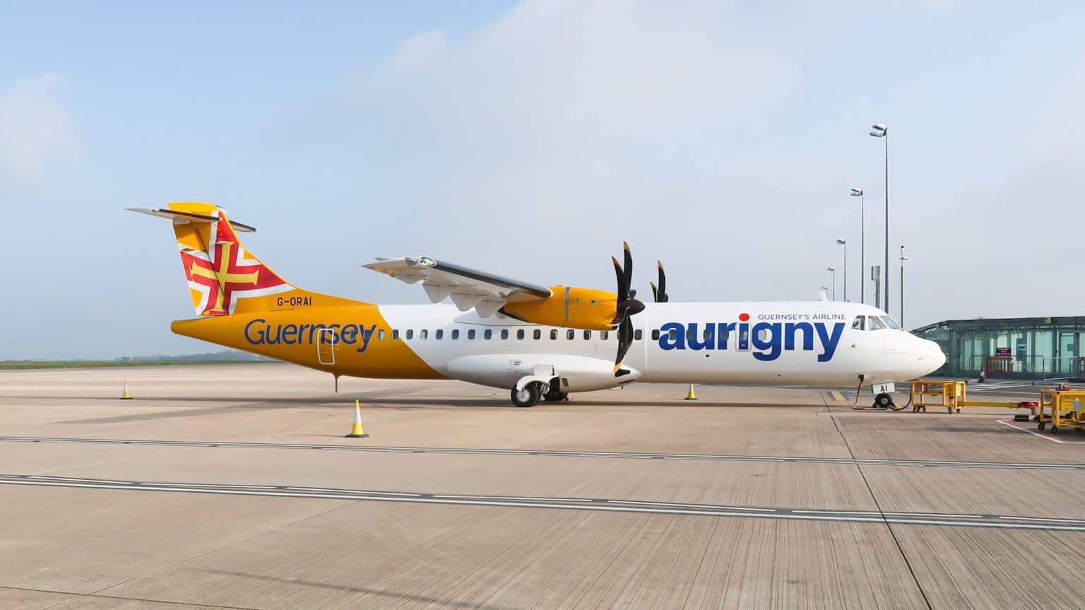Aurigny ATR 72 in yellow and white livery parked on the apron at Guernsey Airport