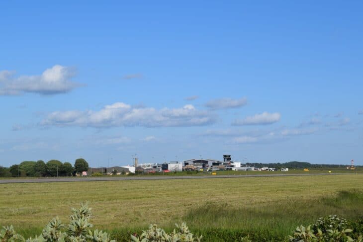 Leeds Bradford Airport terminal and control tower seen across grass from the end of the runway