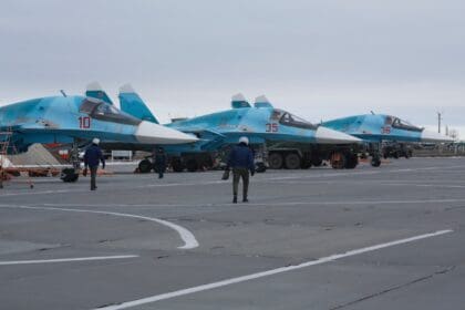 Row of Russian Su-34 strike jets parked on an airbase apron with ground crew beside them