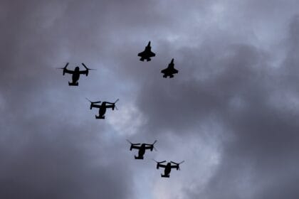 Two Marine Corps F-35B fighters and four MV-22B Ospreys in formation against grey cloud during the Super Bowl LIX flyover