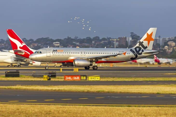 Jetstar Airbus A320 taxiing at Sydney Airport with a Qantas tail behind
