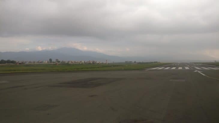 Runway and runway markings at Tribhuvan International Airport with Kathmandu valley hills behind