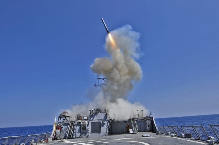 Tomahawk cruise missile climbing away from a US Navy destroyer in a cloud of smoke