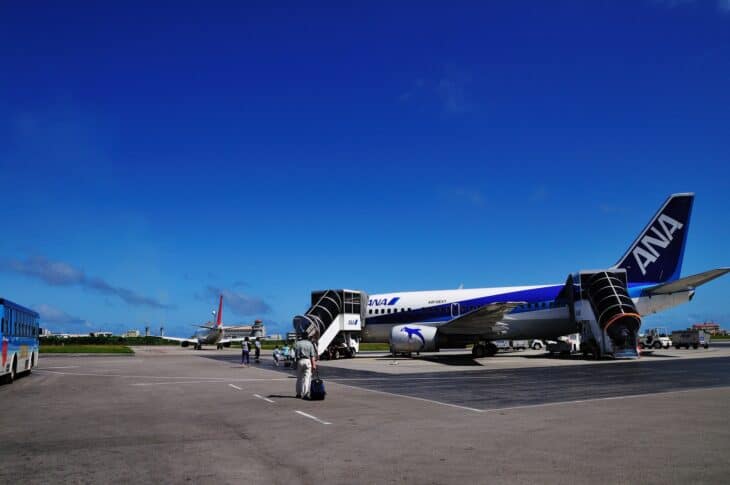 ANA jet parked on the apron at Ishigaki Airport with passengers walking to the aircraft