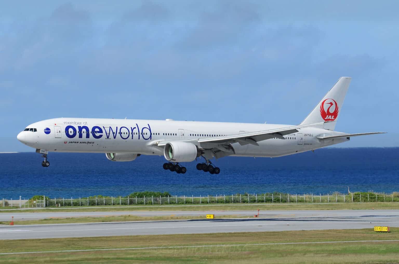 Japan Airlines Boeing 777-300 in oneworld livery on final approach to Naha Airport over the sea