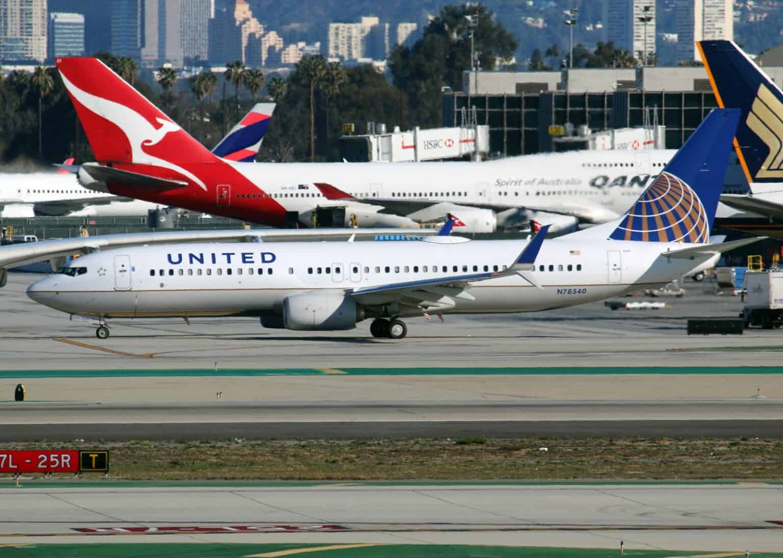 United Airlines Boeing 737-800 N78540 taxiing past parked Qantas and Singapore Airlines jets