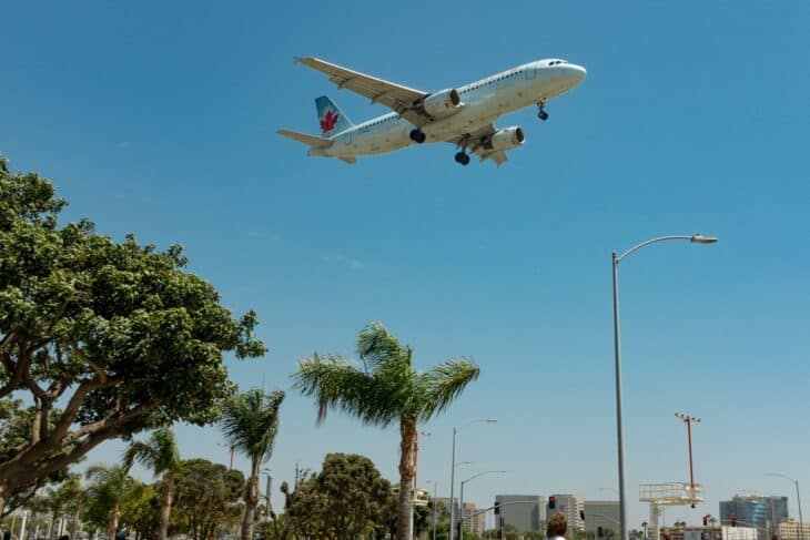 Air Canada Airbus A320 on approach to runway 24R at Los Angeles International Airport over palm trees