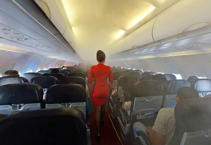 Flight attendant in uniform walking the aisle of an airliner cabin